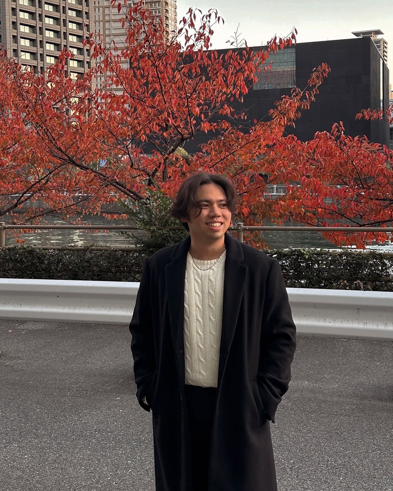 Jericho standing in front of red autumn leaves by a river in Osaka