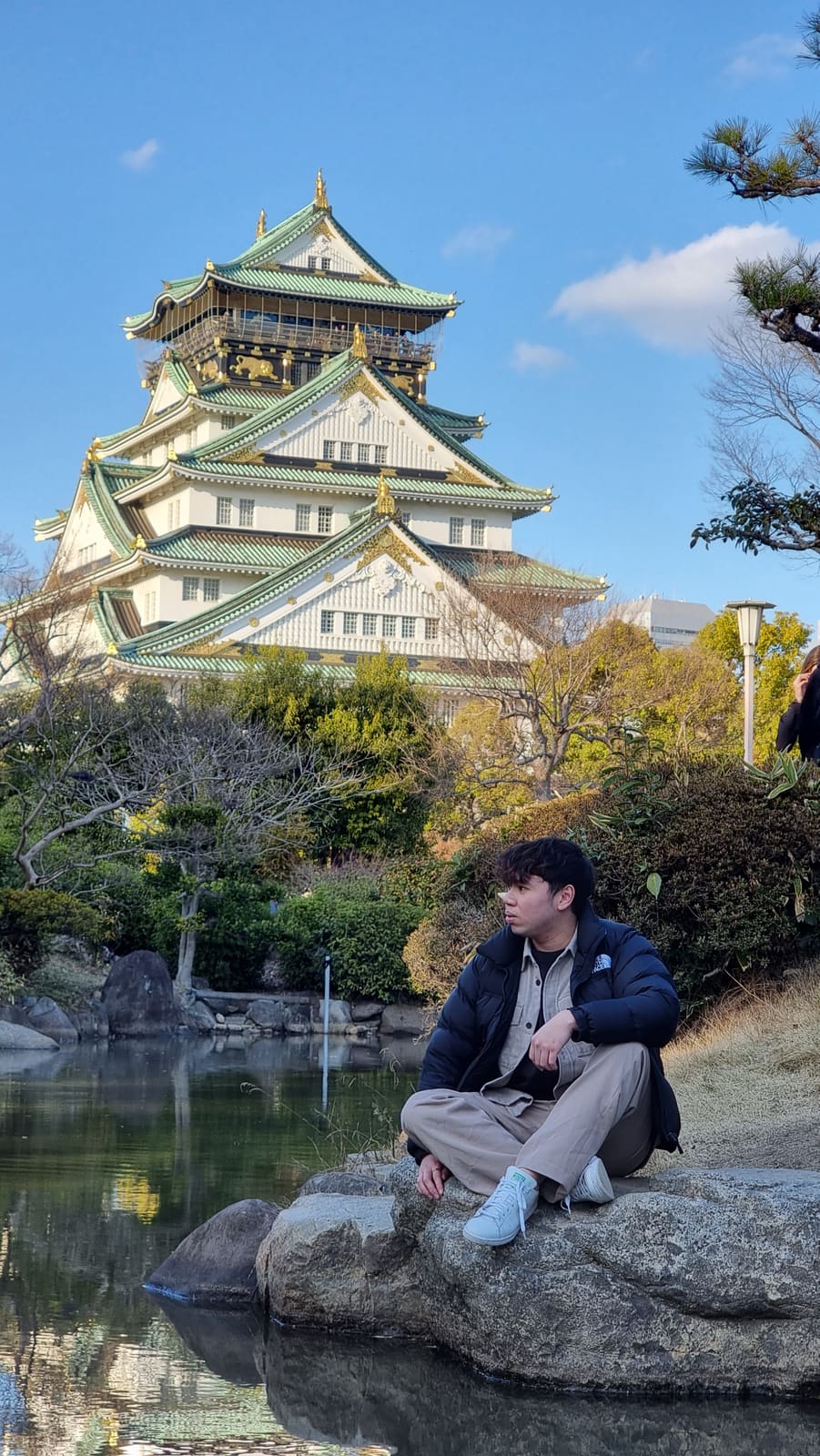 Sitting on the rocks by the moat with Osaka Castle behind