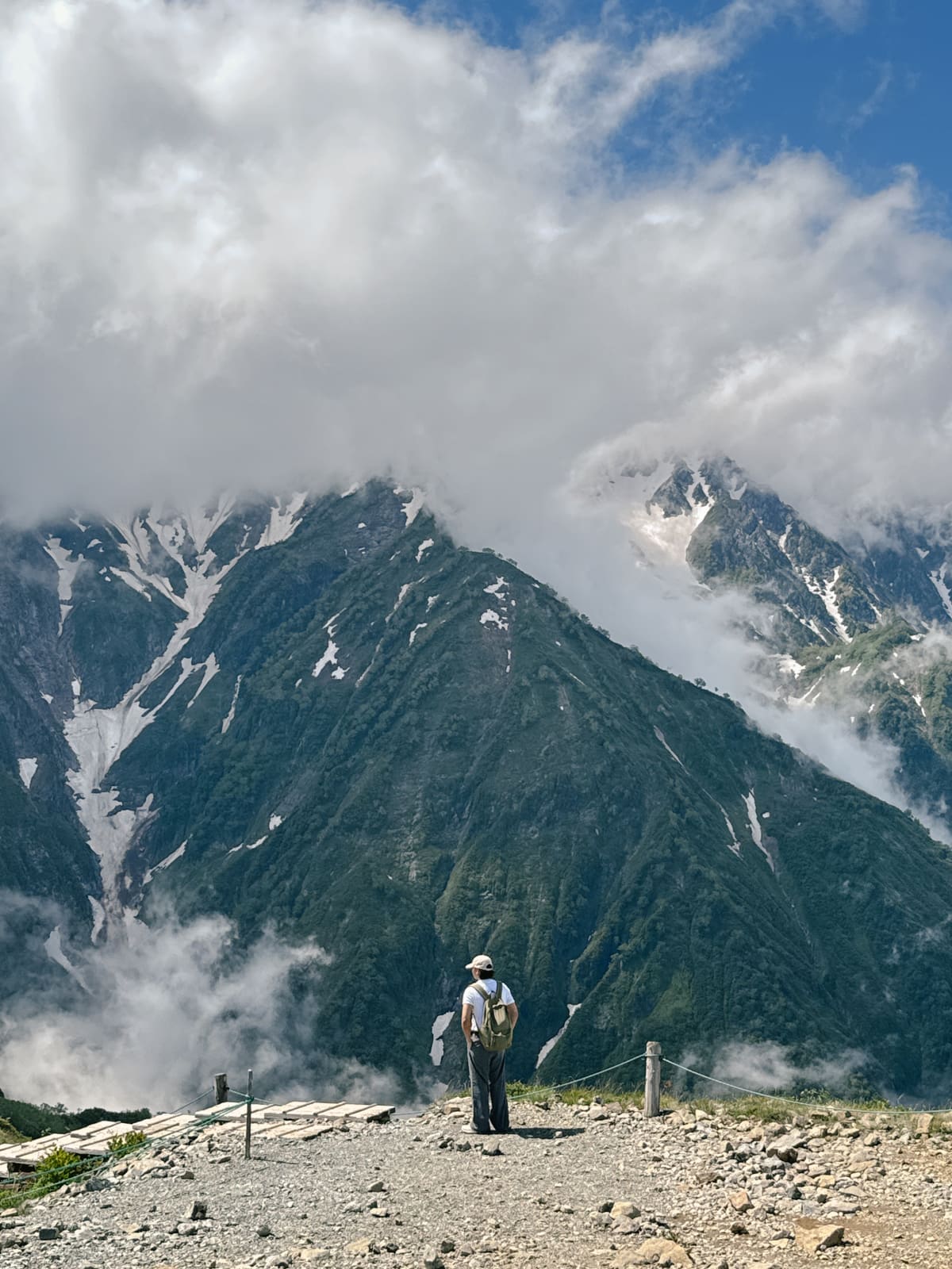 A hiker on a rocky ridge above a cloud-filled valley in the Nagano mountains